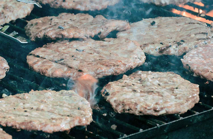 Grilling pork patties over a charcoal grill. 